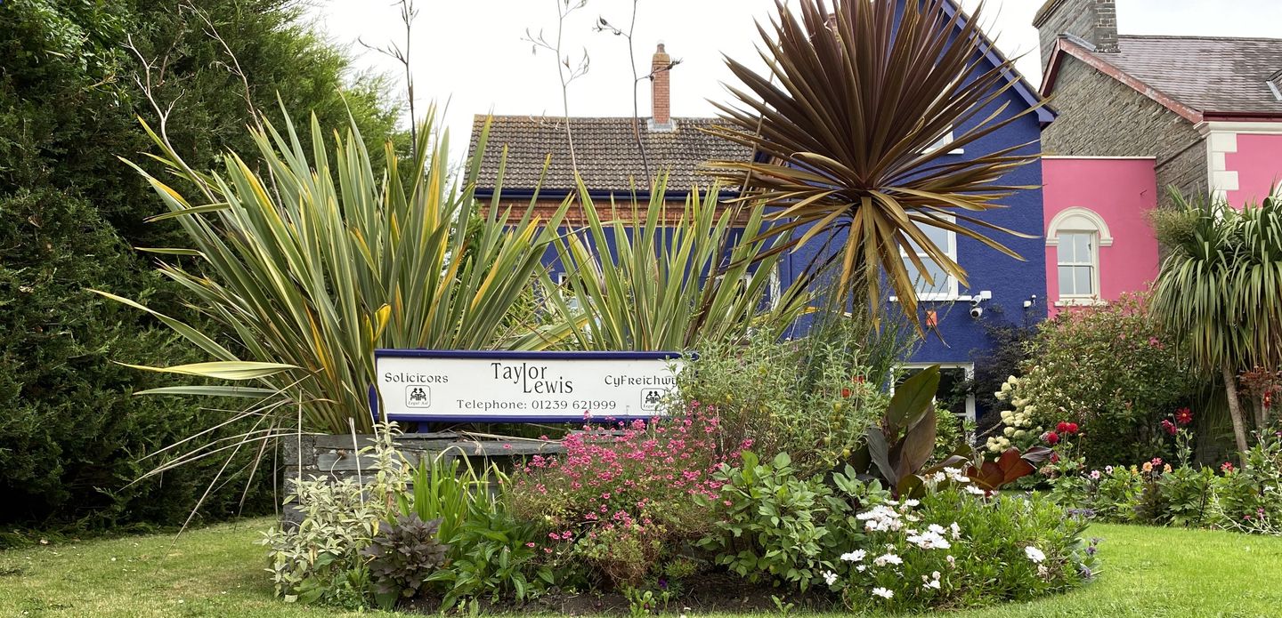 The Taylor Lewis sign in the flowering garden in front of Bingham House, the firm’s blue-painted office on Pendre, Cardigan.